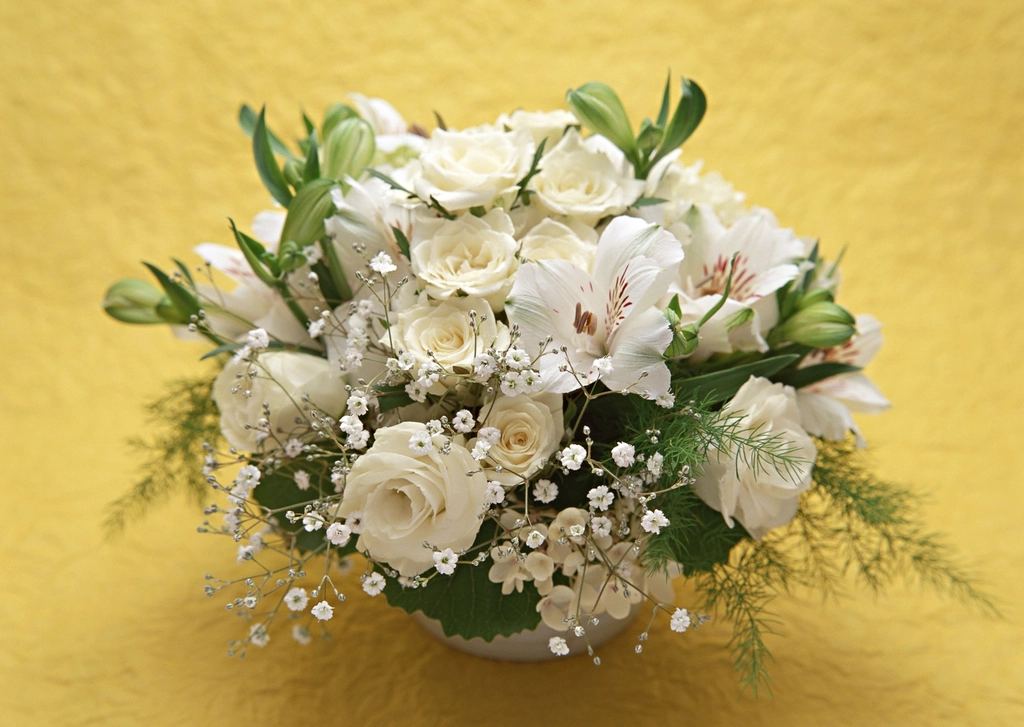 Buchet cu trandafiri albi, crini albi și gypsophila într-un vas alb, pe fundal galben. Imagine ilustrativă.