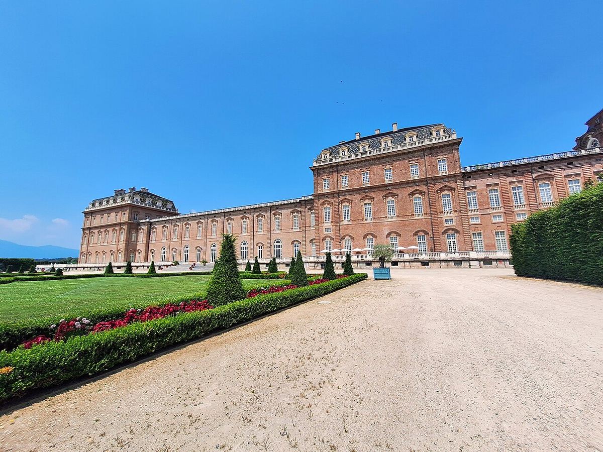 Fațada Reggia di Venaria Reale din Italia, cu grădini geometrice și alei de pietriș sub cer senin.