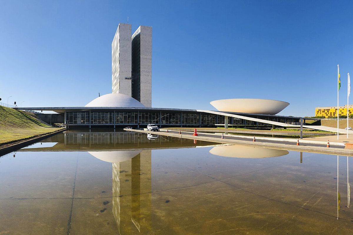 Clădirea Congresului Național din Brasília, cu turnurile gemene și cupolele Camerei Deputaților și Senatului, reflectată în bazin.