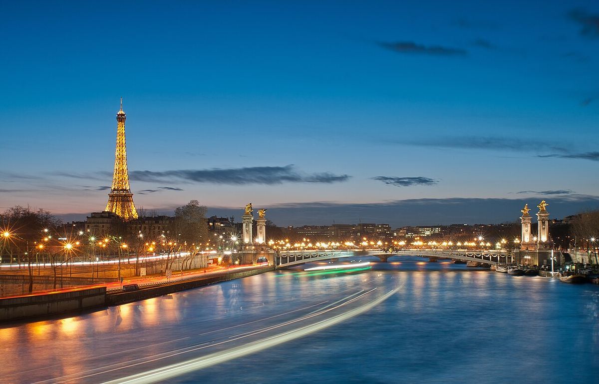 Turnul Eiffel și Podul Alexandru al III-lea iluminate noaptea, peste Sena, în Paris.