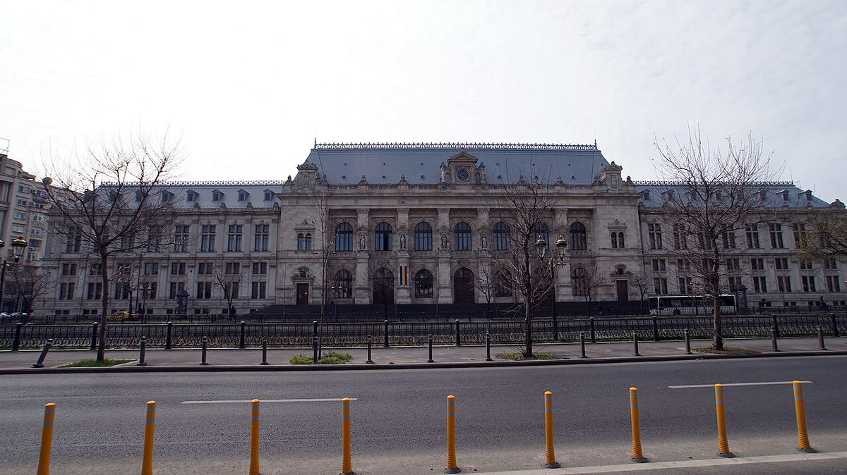 Fațada Palatului de Justiție din București, fotografiată ziua, cu trotuar și stâlpi galbeni în prim-plan.