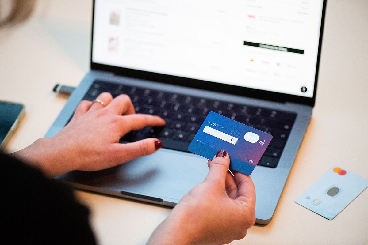 O persoană folosește un card bancar și un laptop pentru a face cumpărături online.
