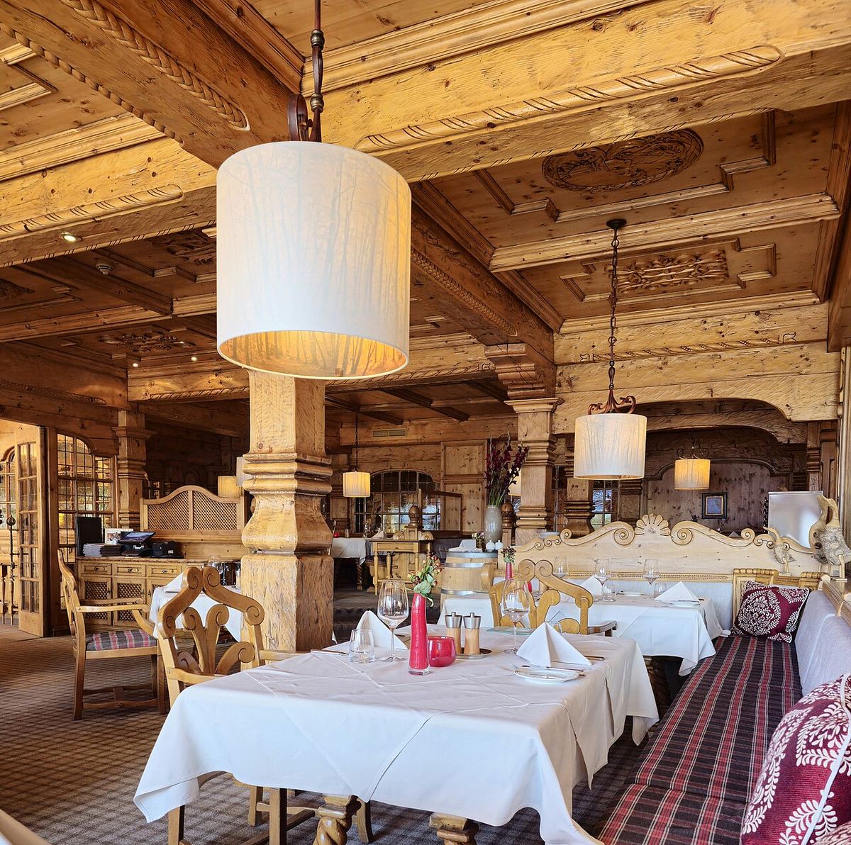 Interiorul unui restaurant cu mese și scaune din lemn, aranjate pentru clienți, într-o sală cu ferestre.