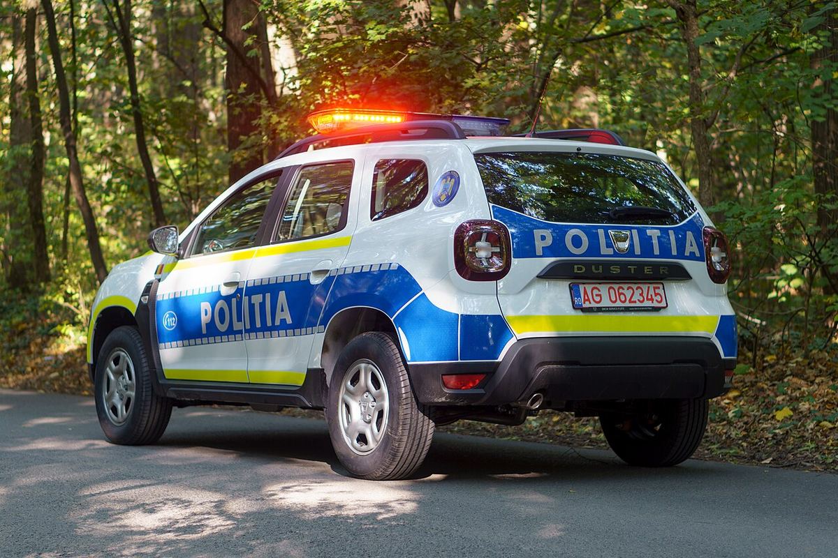 Autoturism Dacia Duster al Poliției Române, în livrea albastru-galben, fotografiat din spate.