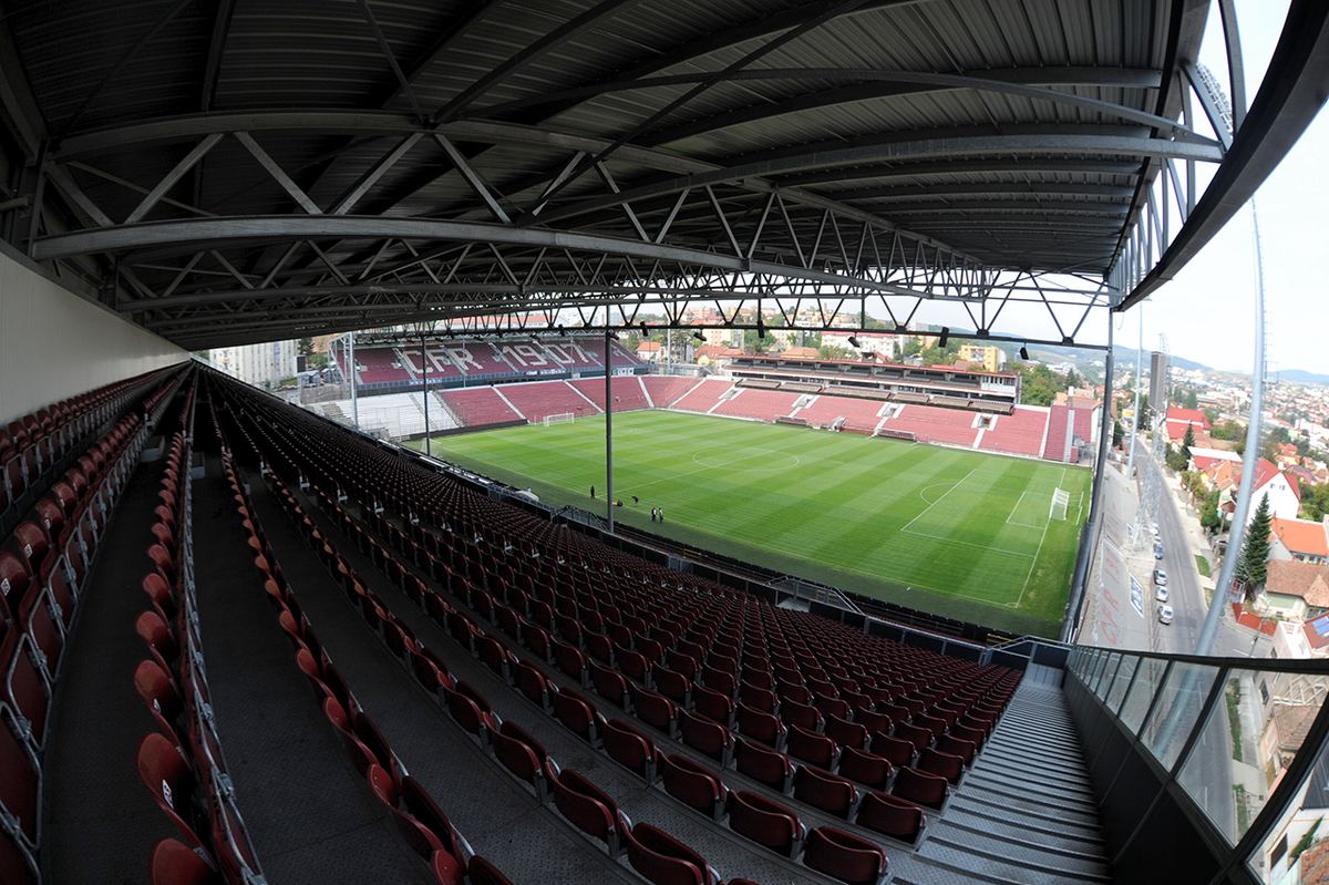 Stadionul Dr. Constantin Rădulescu din Cluj-Napoca, gol, cu tribune cu scaune roșii și gazon verde.