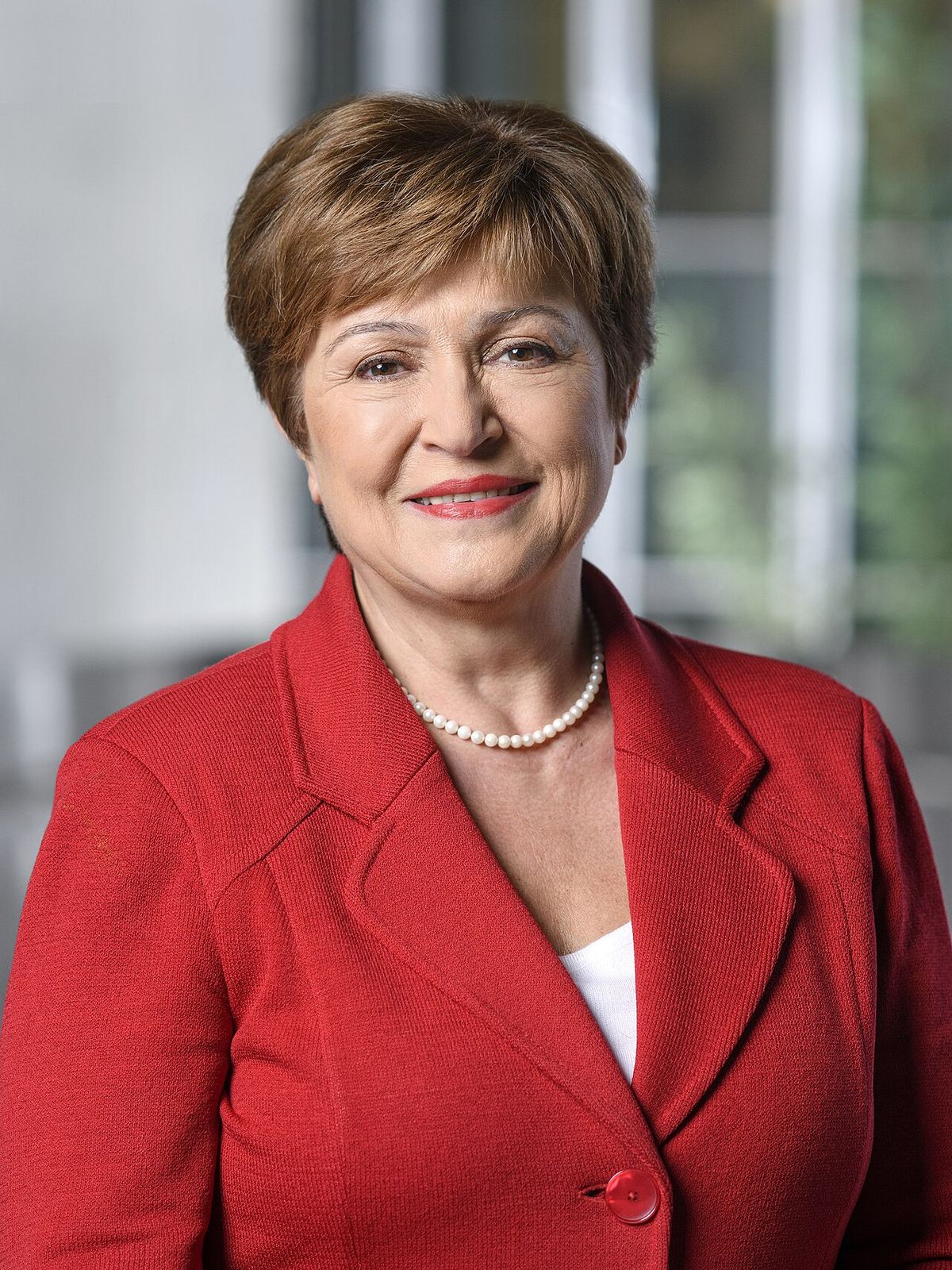 Portretul Kristalinei Georgieva, într-un sacou roșu și cu un colier de perle, zâmbind către cameră.