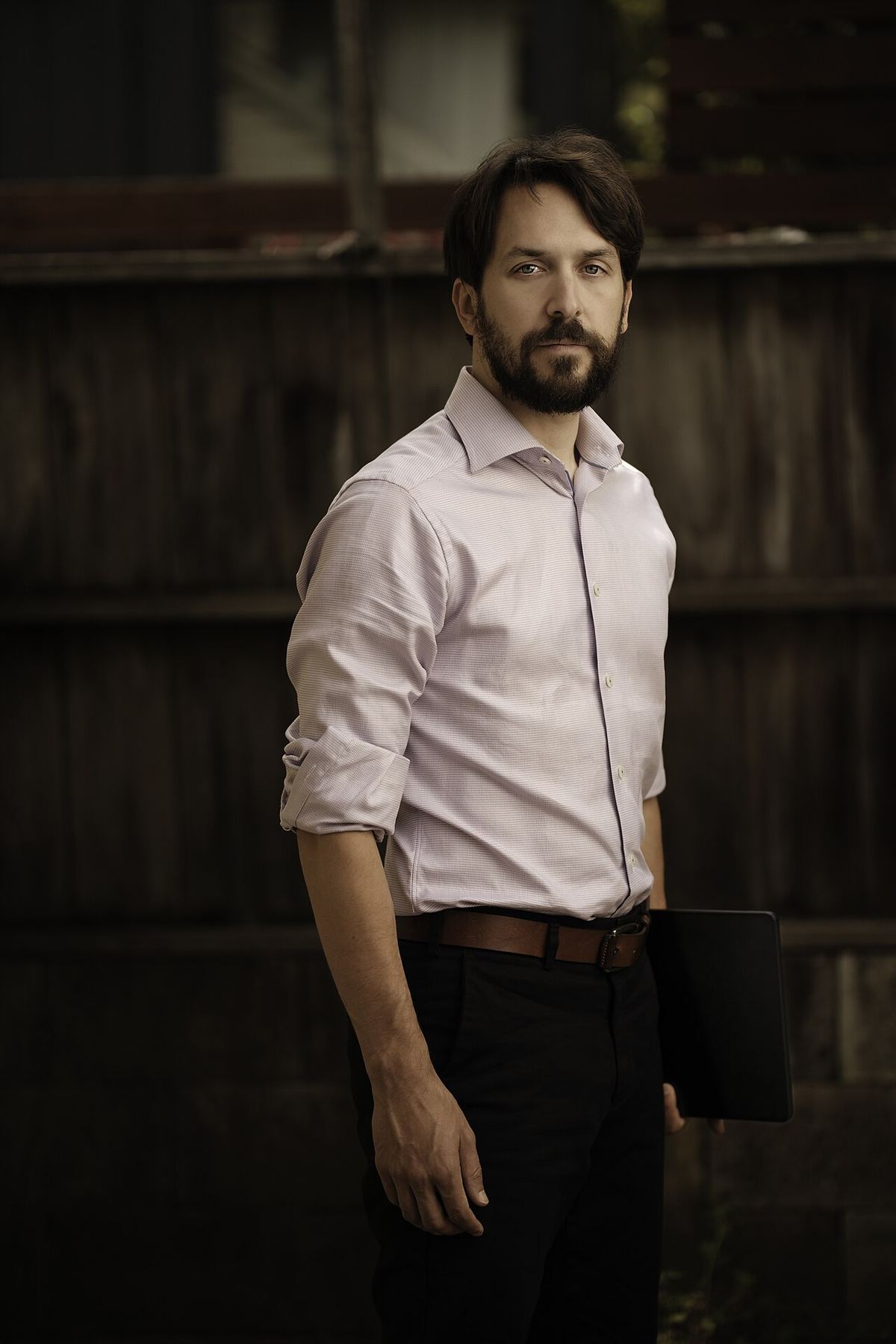 Nate Soares, director al MIRI, în picioare afară, în fața unui gard de lemn, în portret de corp întreg.