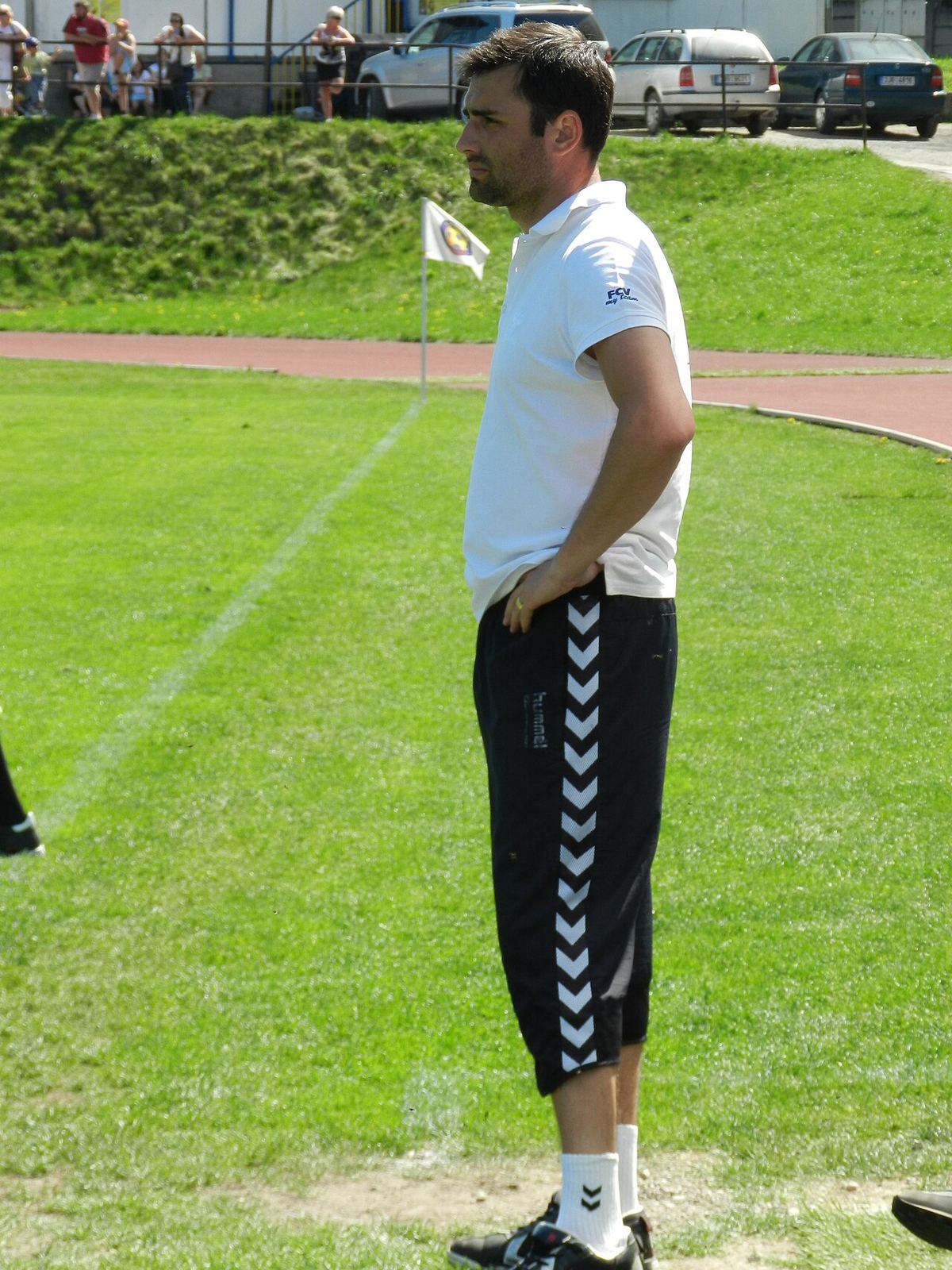 Antrenorul David Oulehla pe un teren de fotbal, în tricou alb și pantaloni scurți negri (fotografie de arhivă).