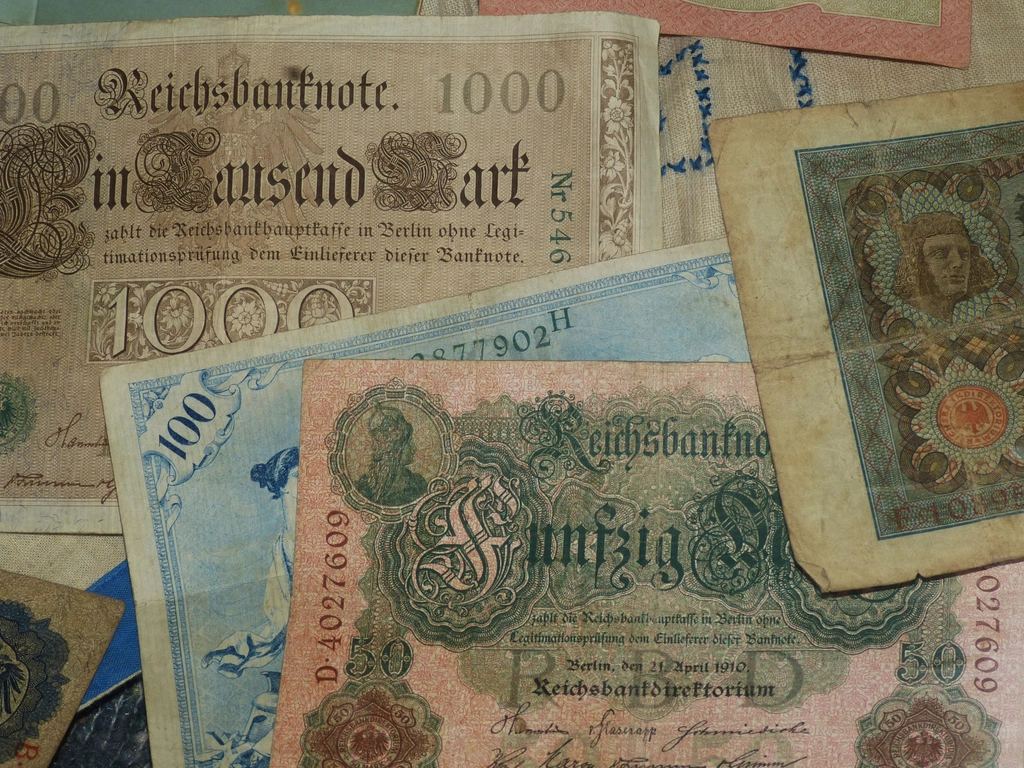 Bancnote vechi de hârtie, emise de Reichsbank, suprapuse pe o masă, cu desene colorate vizibile.