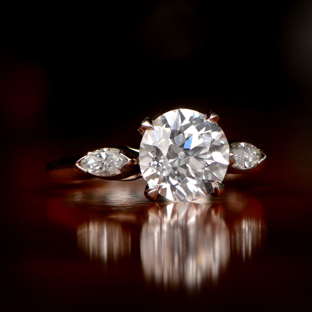 Inel din platină cu diamant central mare și două diamante laterale, pe fundal întunecat (fotografie de arhivă).
