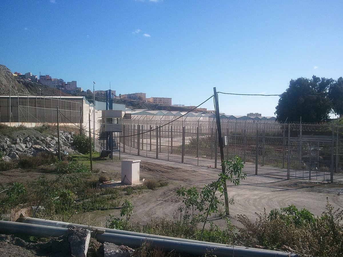 Gard de frontieră cu sârmă ghimpată la granița dintre Ceuta și Maroc, fotografiat ziua, pe un teren deschis.
