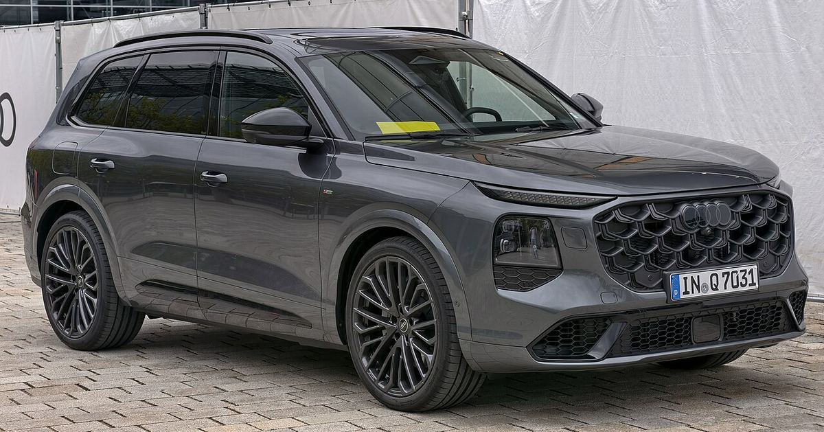 Audi Q7 3.0 TDI quattro S line, SUV de culoare închisă parcat, văzut din față-lateral.