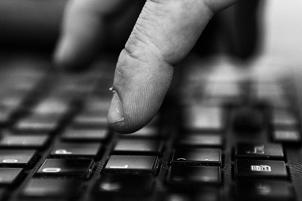 Degete pe tastatura unui calculator, în semiîntuneric