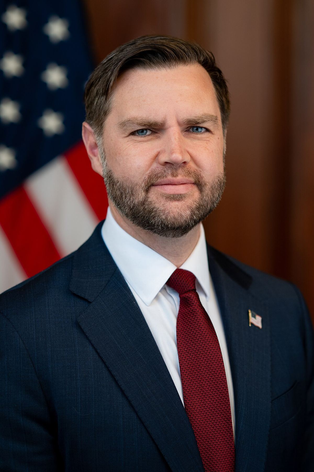 Portretul oficial al vicepreședintelui american JD Vance, în fața unui steag american, într-un birou oficial.